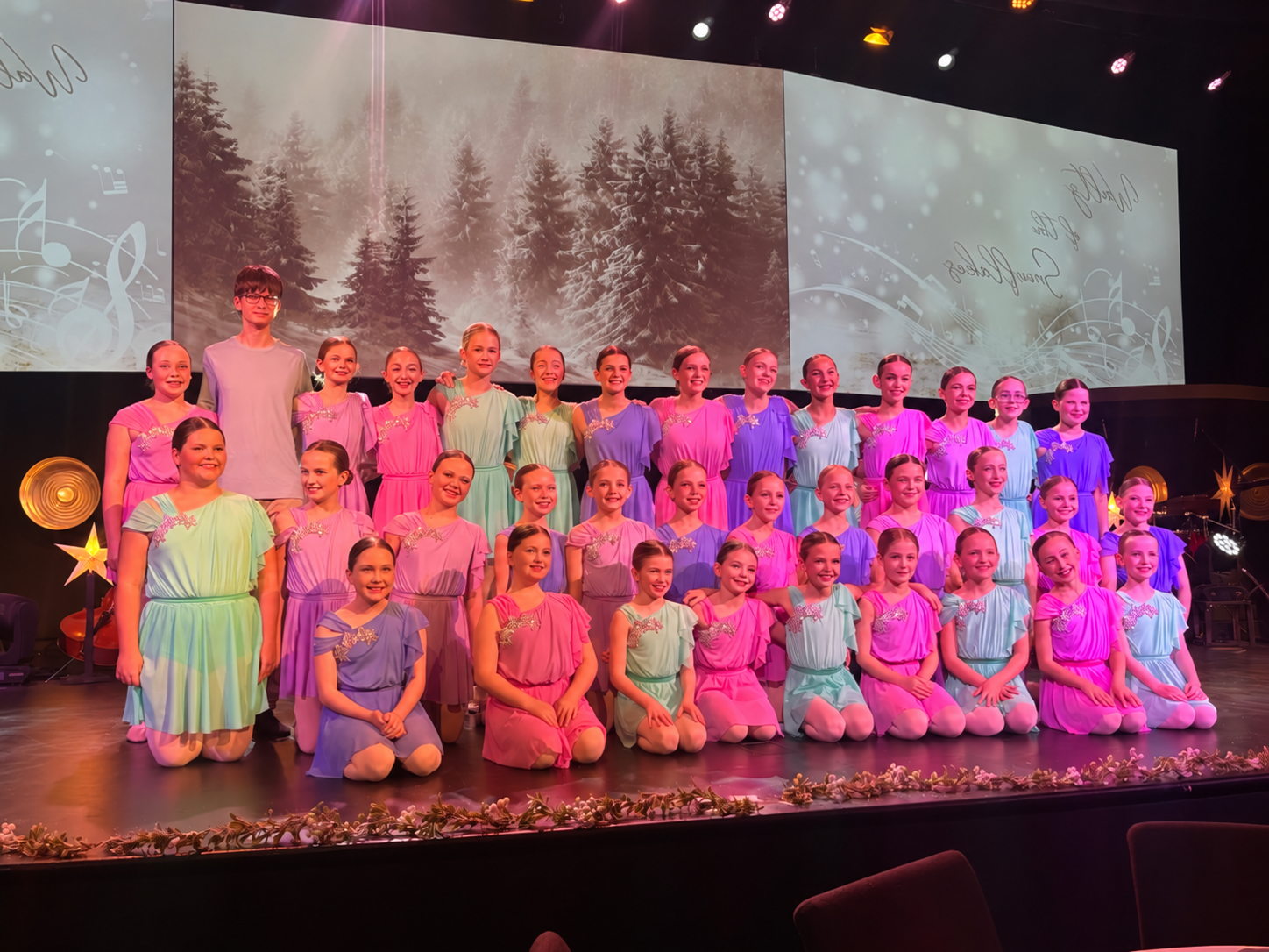 Collective dancers in pastel costumes posing on stage at a ballet production, horizontally mirrored.