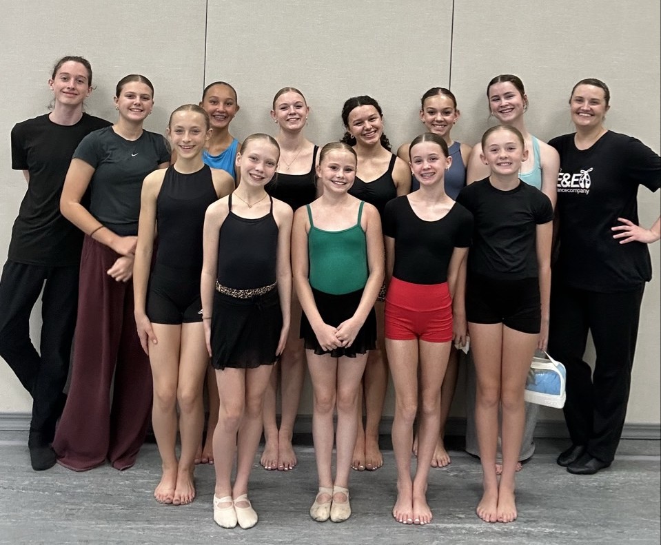 Tween and teen dancers and teachers smiling together in dancewear in the E&E Dance Company studio.